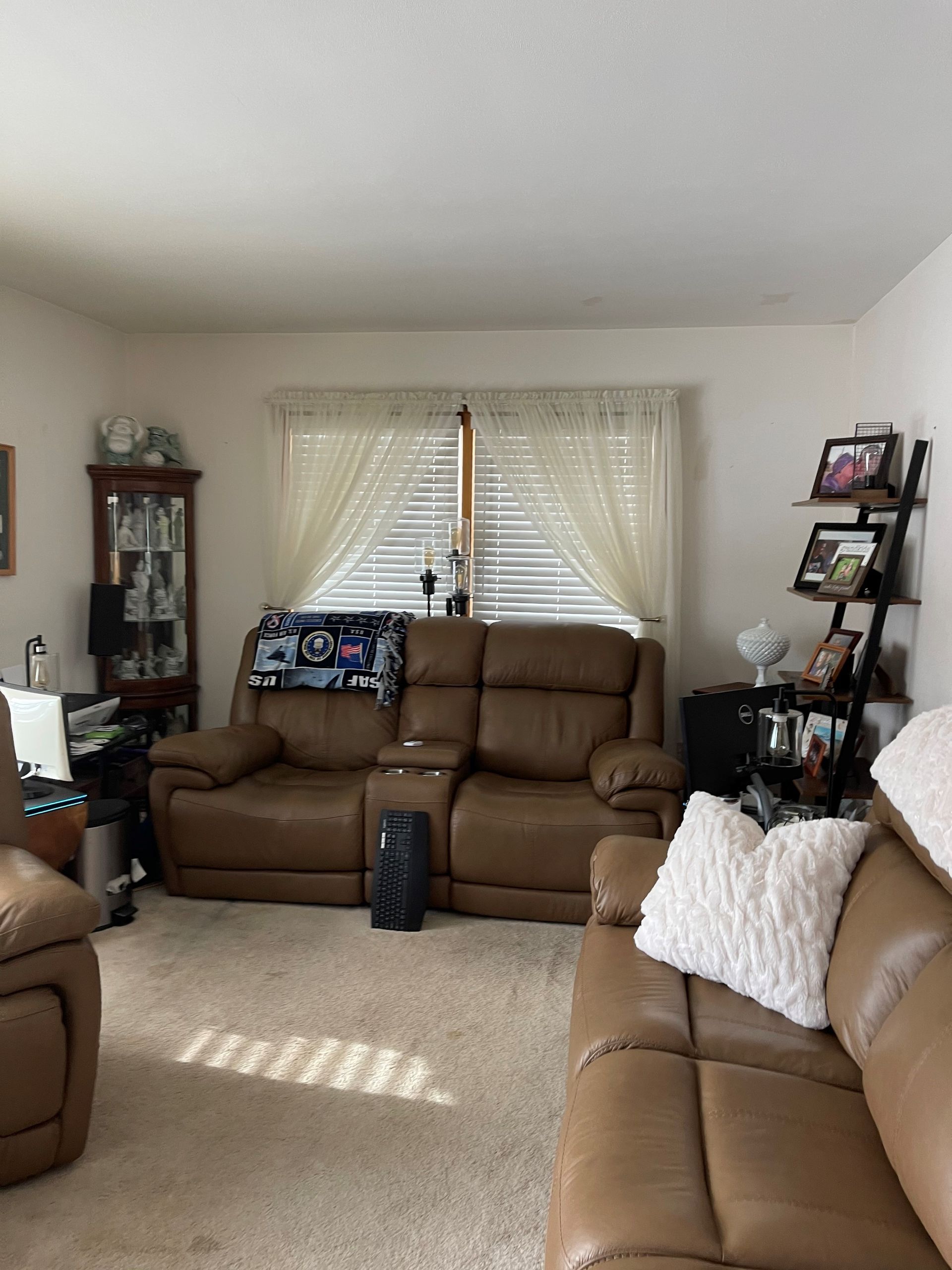 A living room with a couch , chairs , and a window.