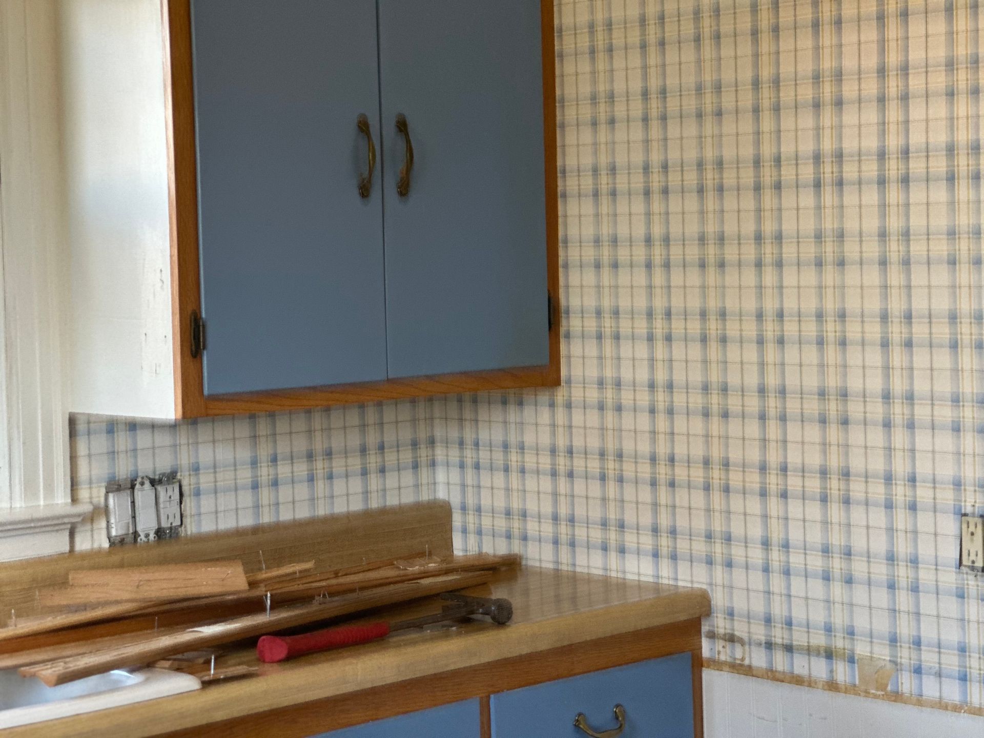 A kitchen with blue cabinets and a hammer on the counter