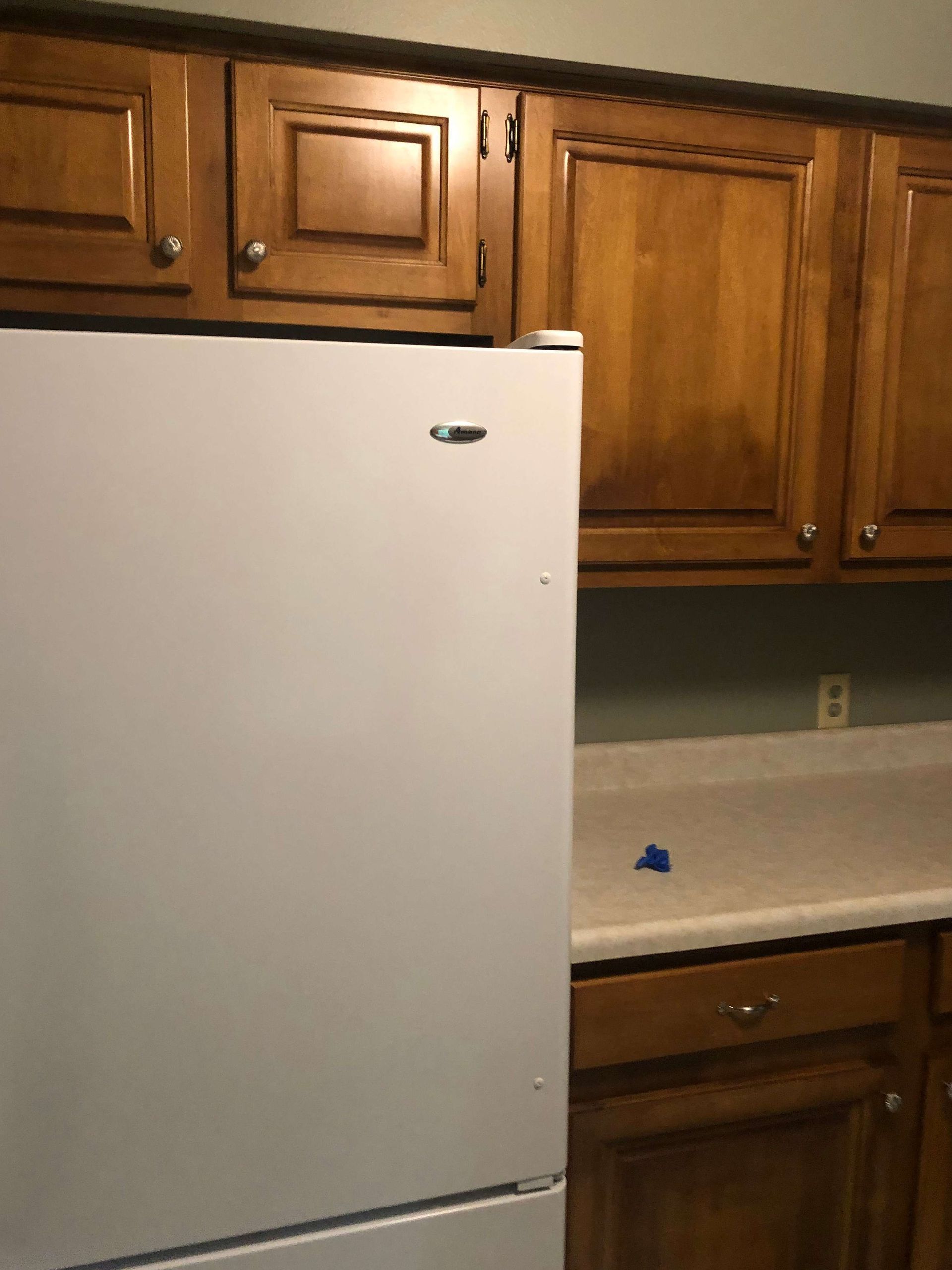 A white refrigerator in a kitchen with wooden cabinets