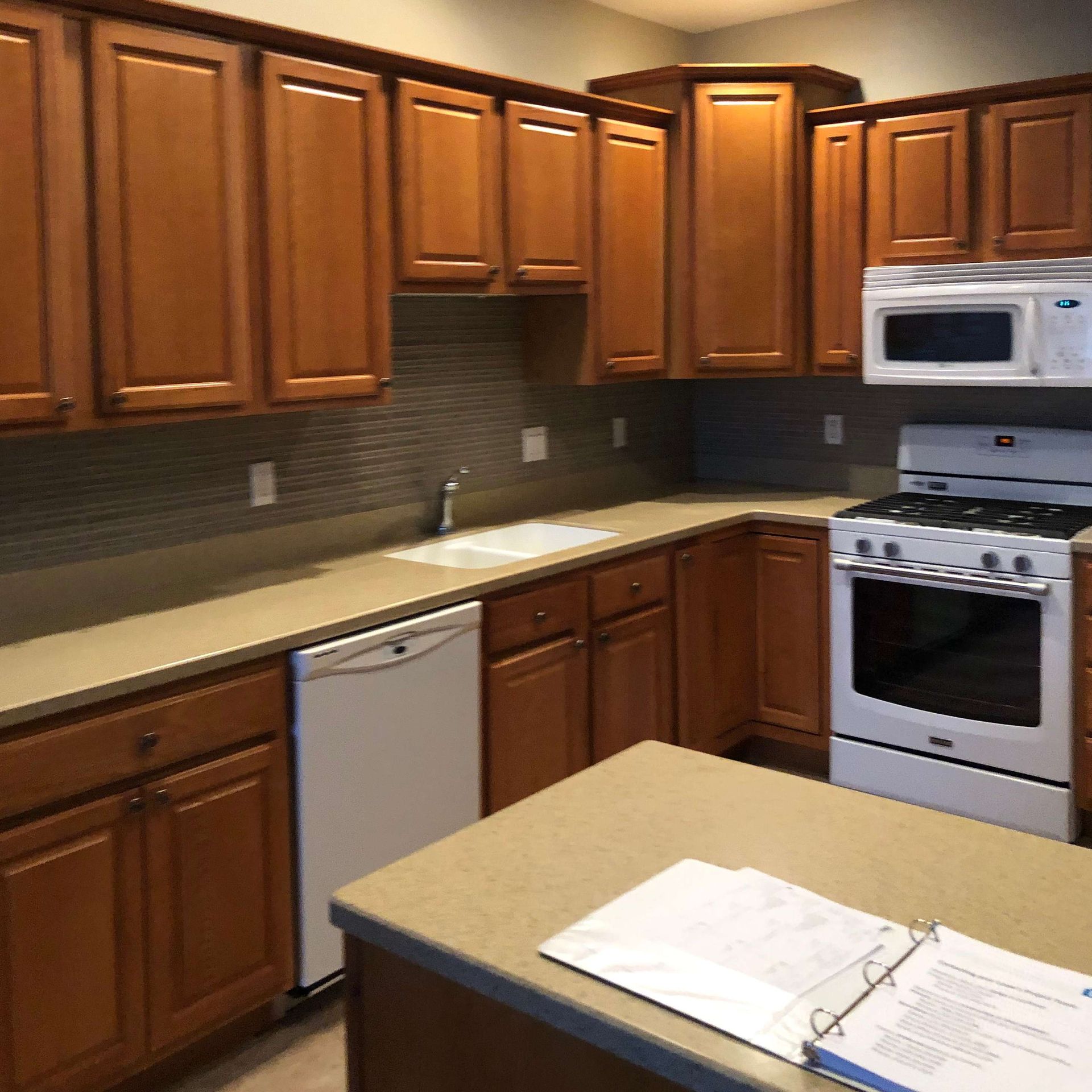 A kitchen with wooden cabinets , a stove , a microwave and a sink.