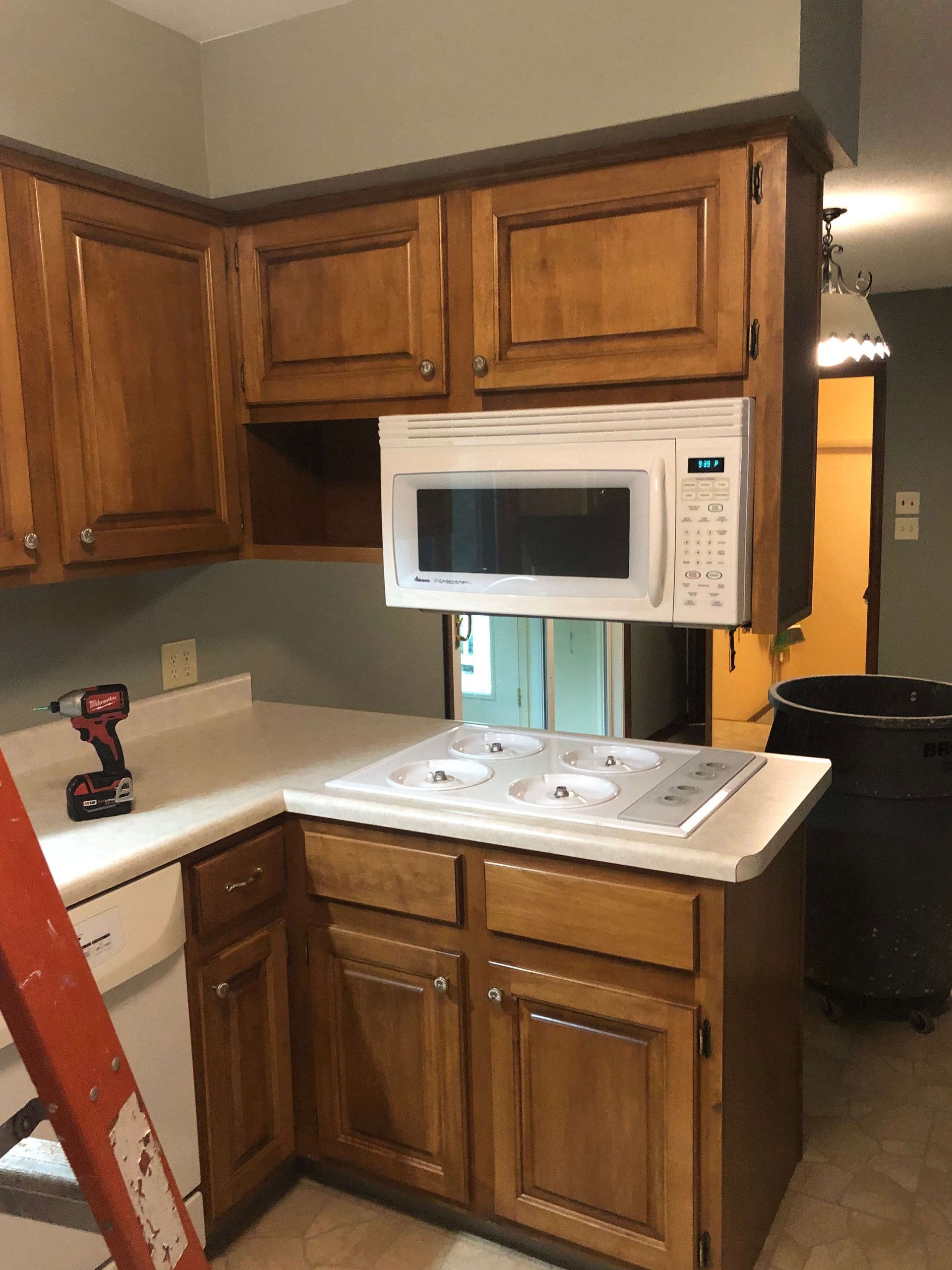 A kitchen with wooden cabinets and a microwave above the stove