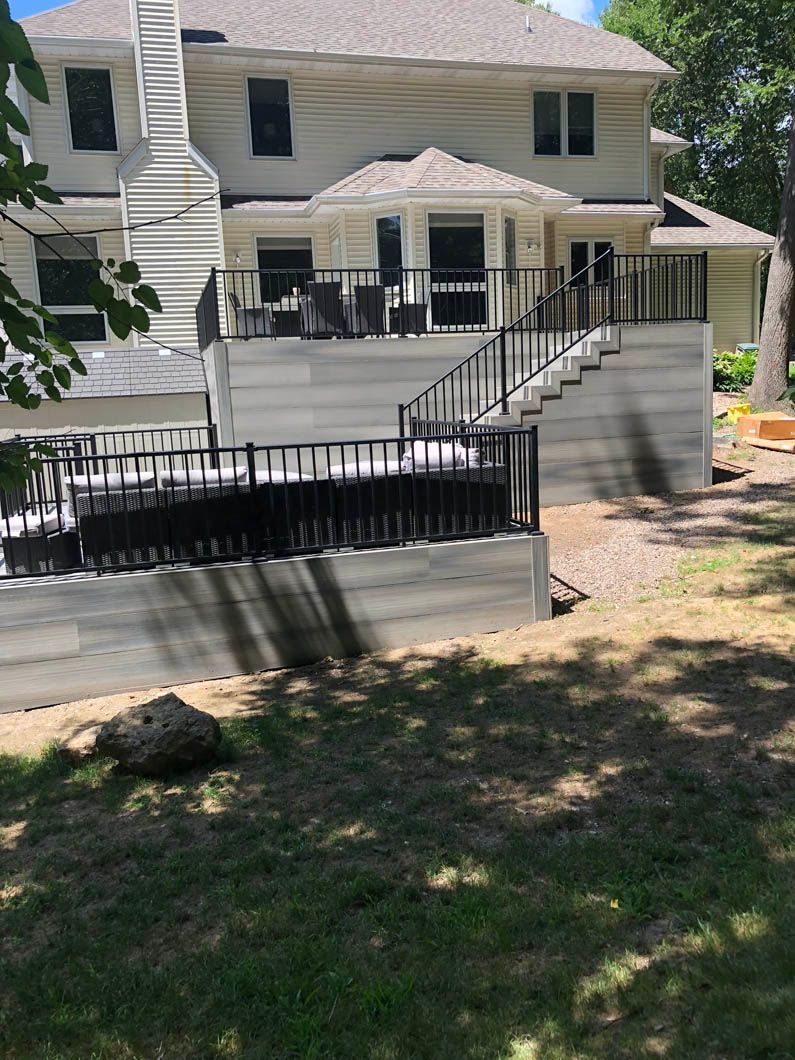 A large white house with a large deck and stairs leading up to it.