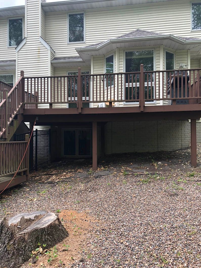 The back of a house with a wooden deck and stairs.