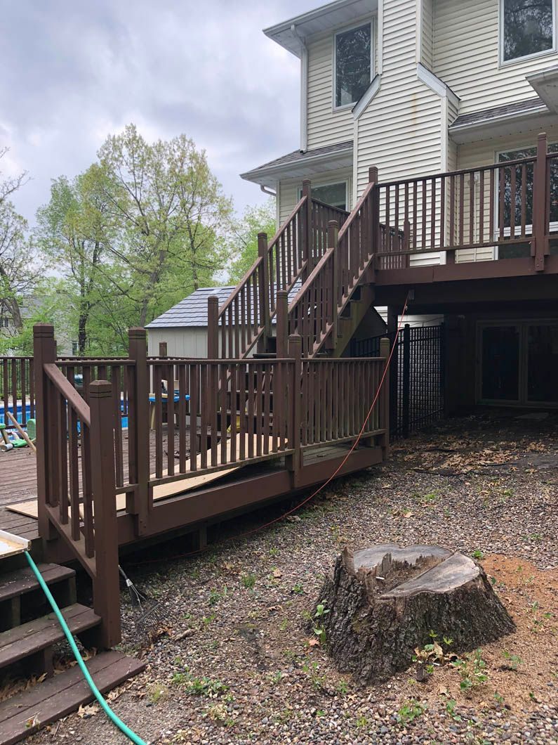 A wooden deck with stairs and a hose in front of a house.