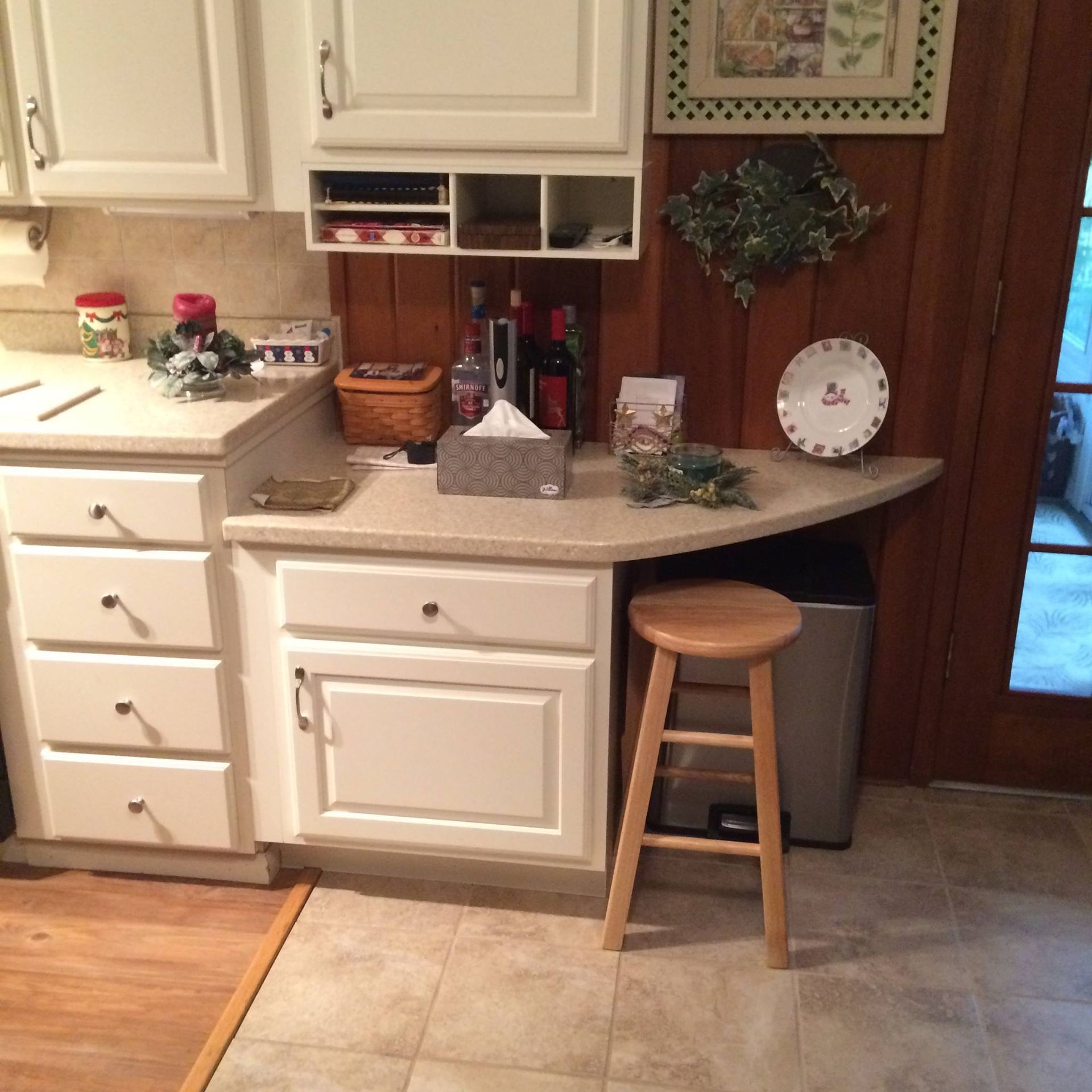 A kitchen with white cabinets and a wooden stool