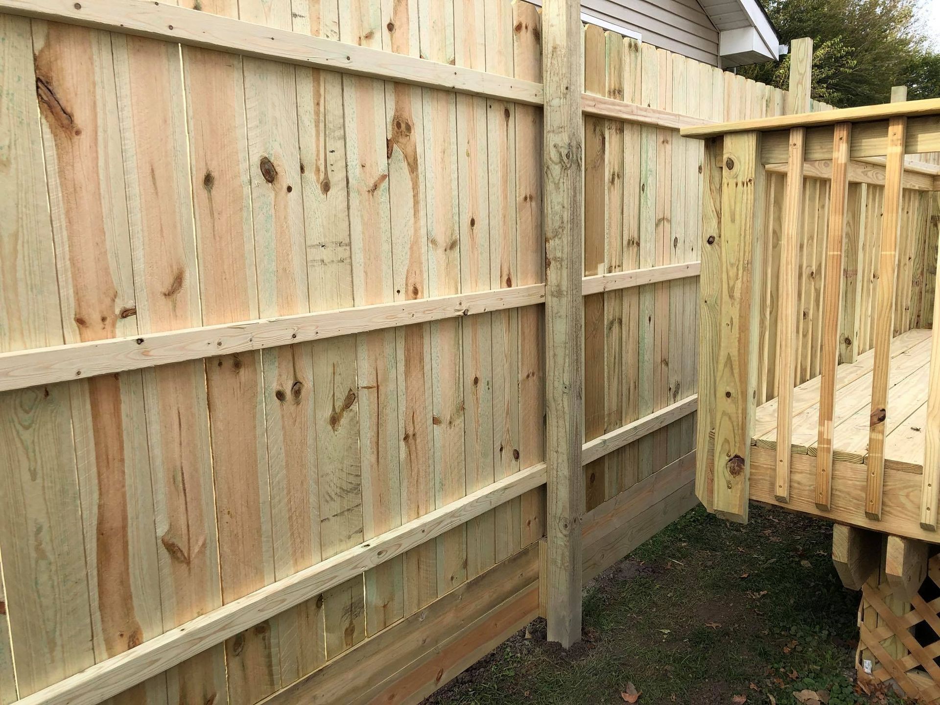 A wooden fence is next to a wooden deck.