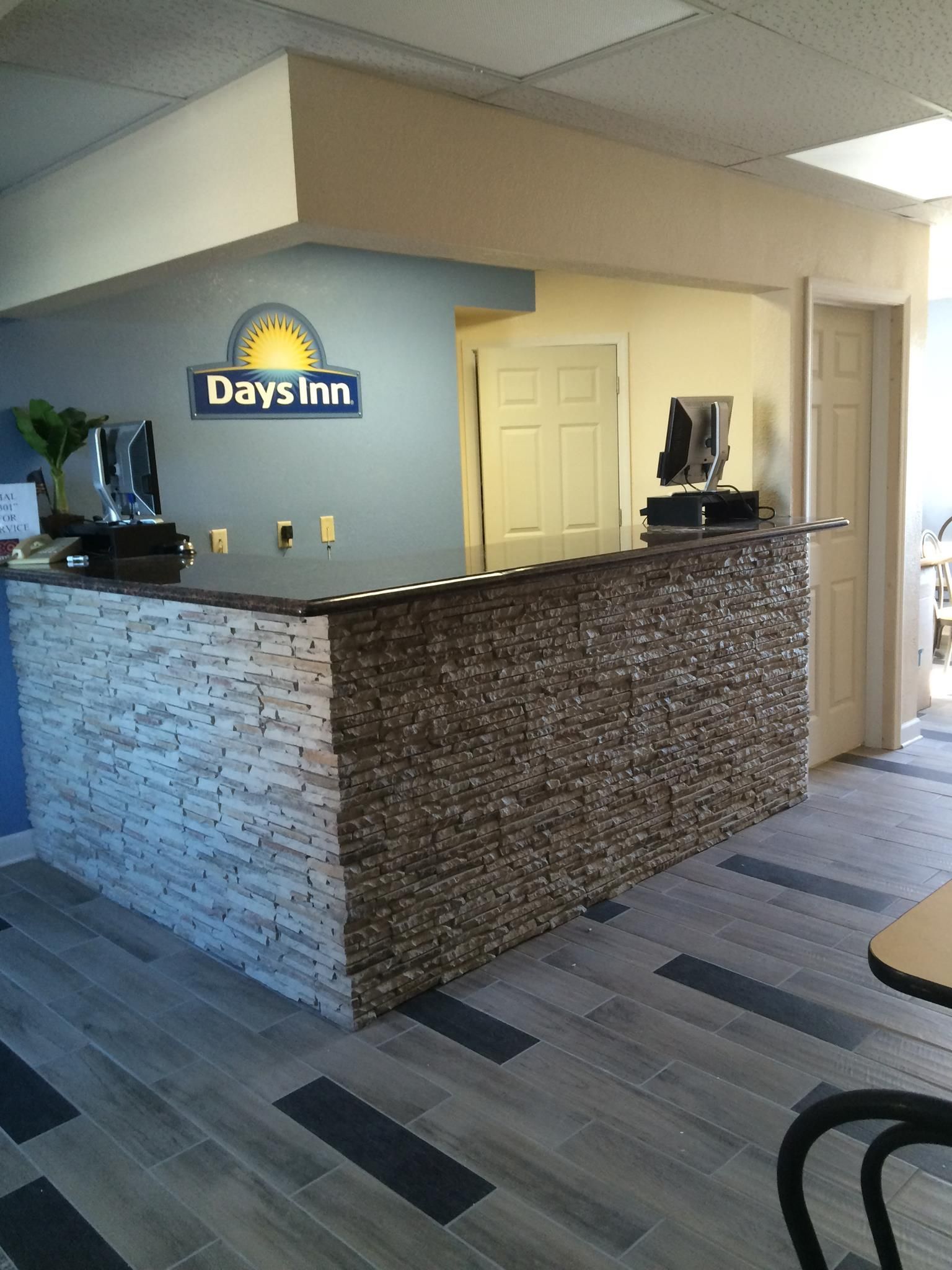 A day inn hotel lobby with a brick counter and a sign on the wall.