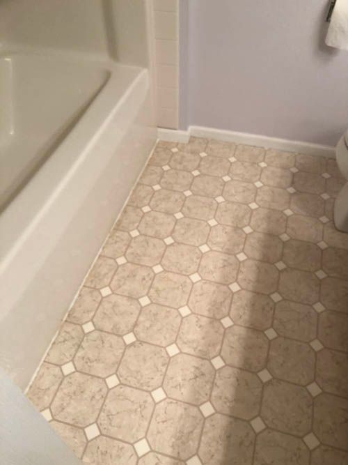 A bathroom with a tiled floor and a bathtub.