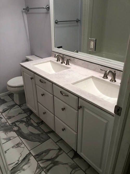 A bathroom with two sinks , a toilet , and a mirror.
