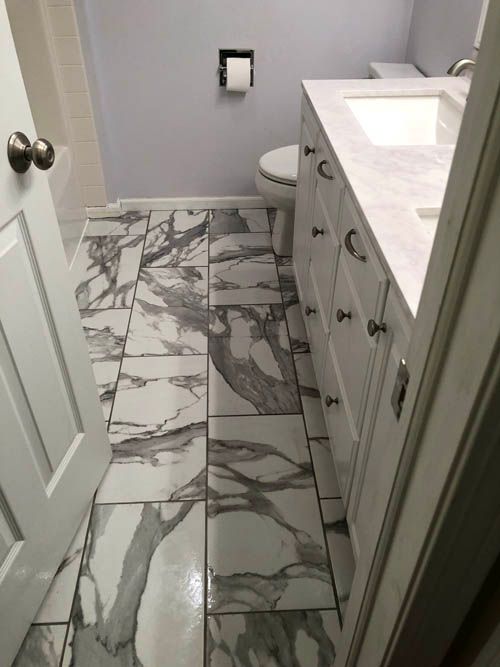 A bathroom with a sink , toilet , and marble floor tiles.