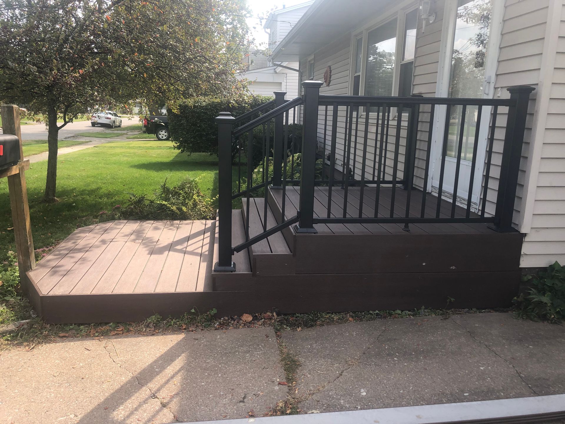 A porch with a black railing and stairs next to a house.