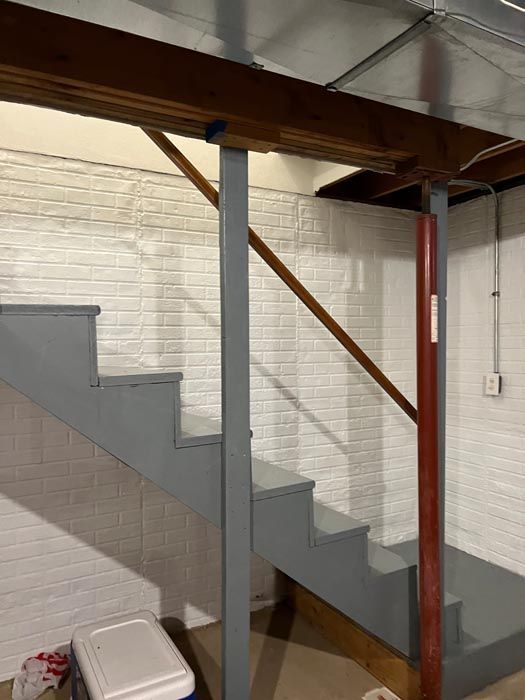 A staircase in a basement with a cooler on the floor.