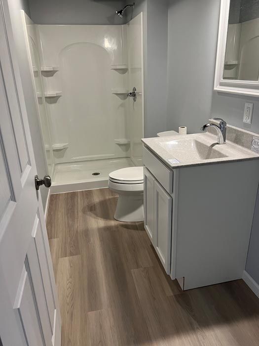 A bathroom with a toilet , sink , shower and mirror.