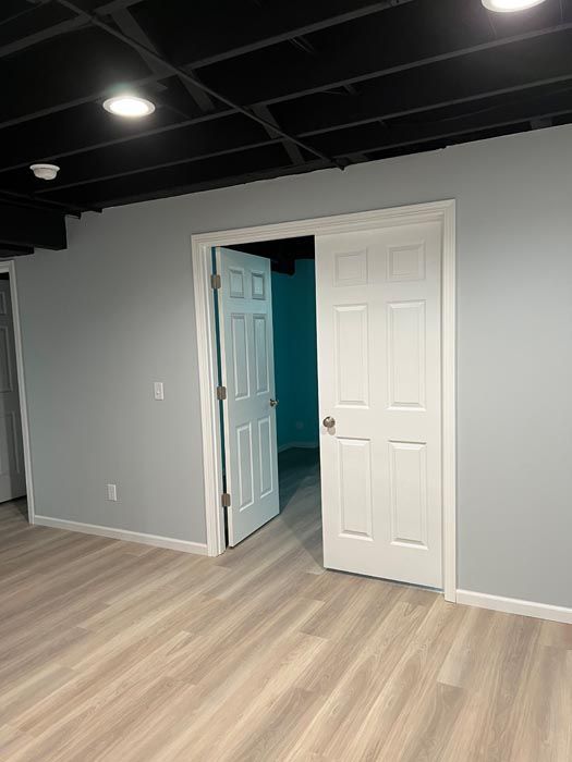 An empty room with hardwood floors and a white door.