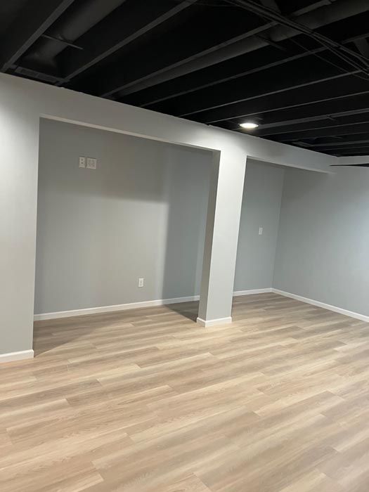 An empty basement with hardwood floors and a black ceiling.