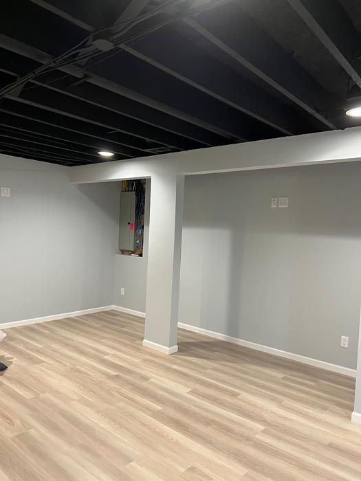 An empty basement with hardwood floors and a black ceiling.