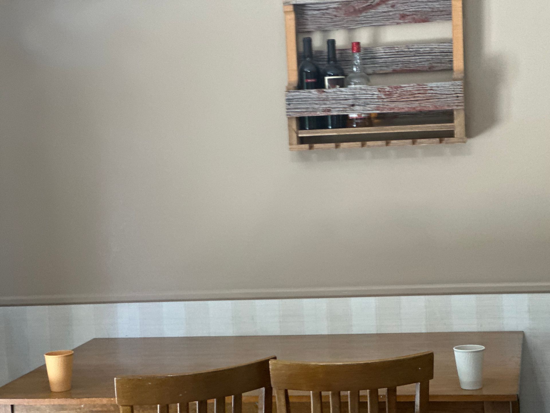 A table and chairs in a room with a wine rack on the wall