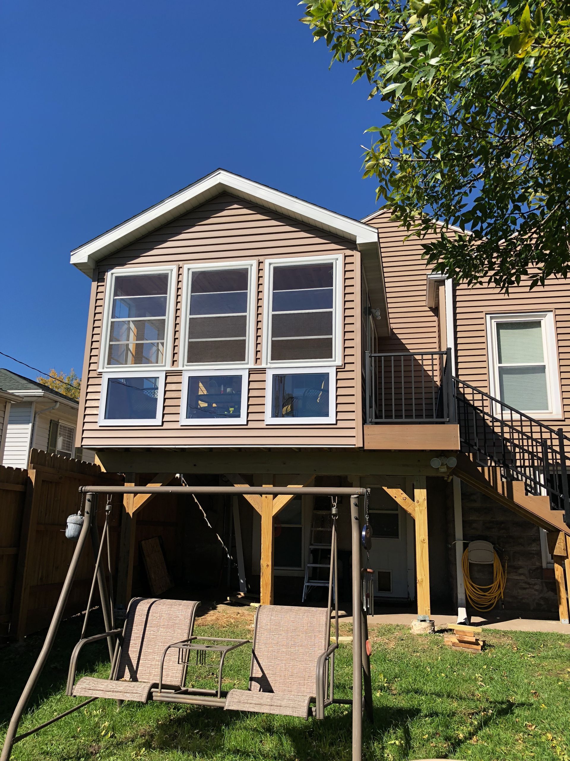 The back of a house with a swing set in front of it.