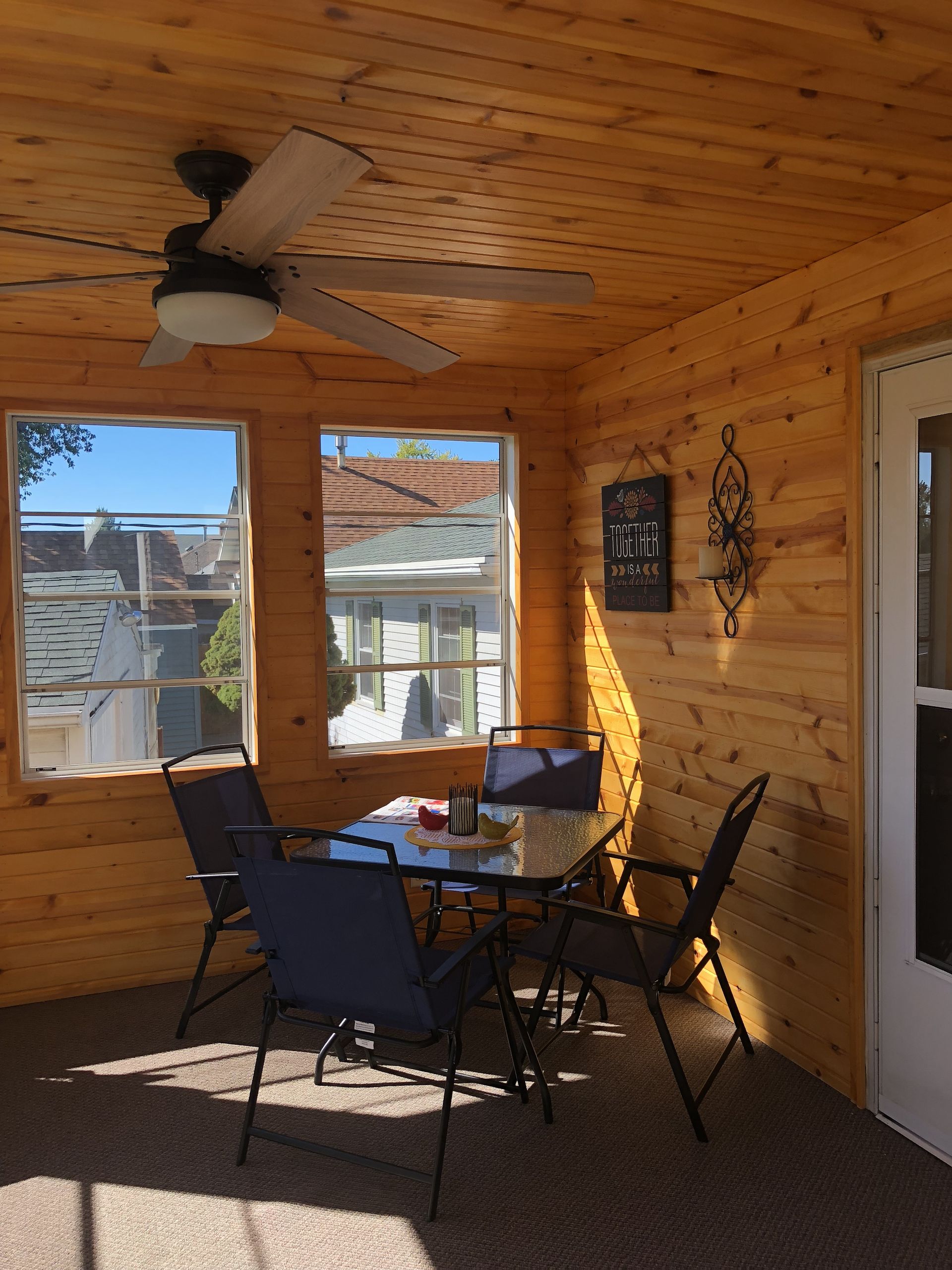 A porch with a table and chairs and a ceiling fan.