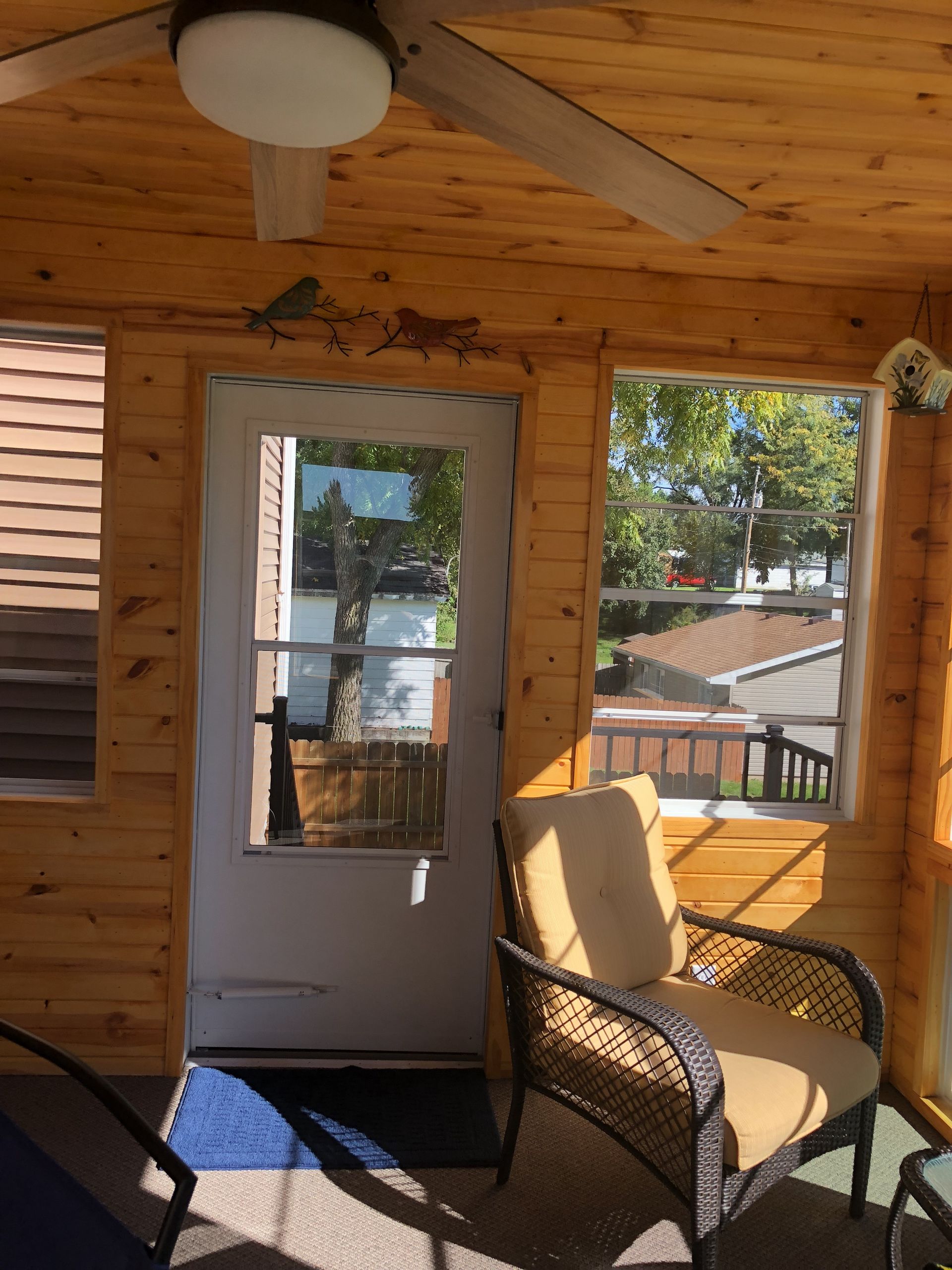 A screened in porch with a chair and a ceiling fan