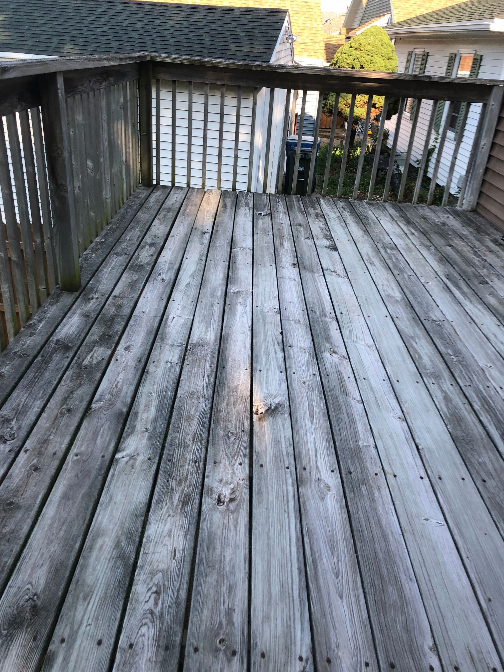A wooden deck with a railing and a roof in the background.