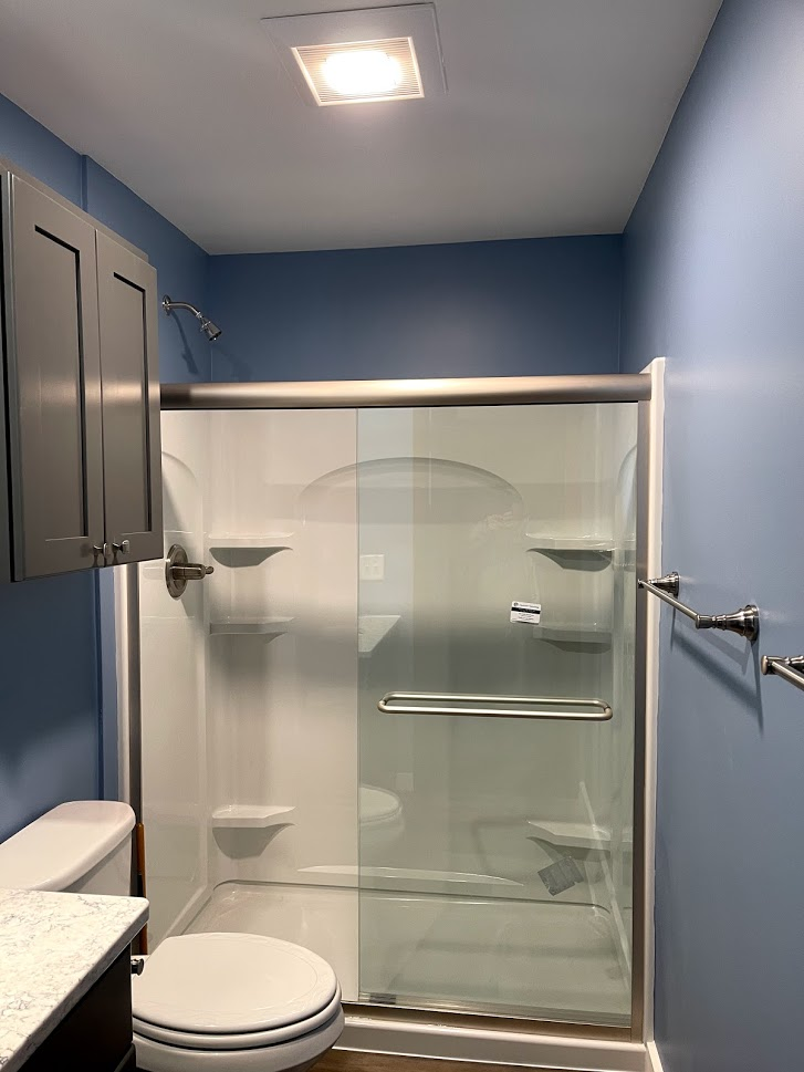A bathroom with a toilet , shower , and cabinets.