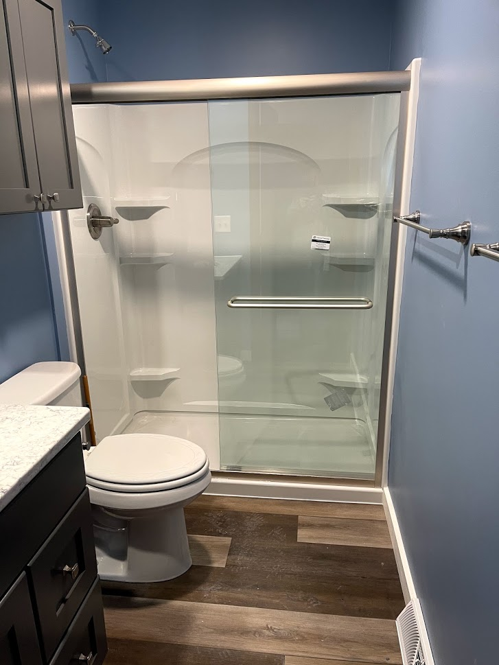 A bathroom with a toilet , sink and shower stall.