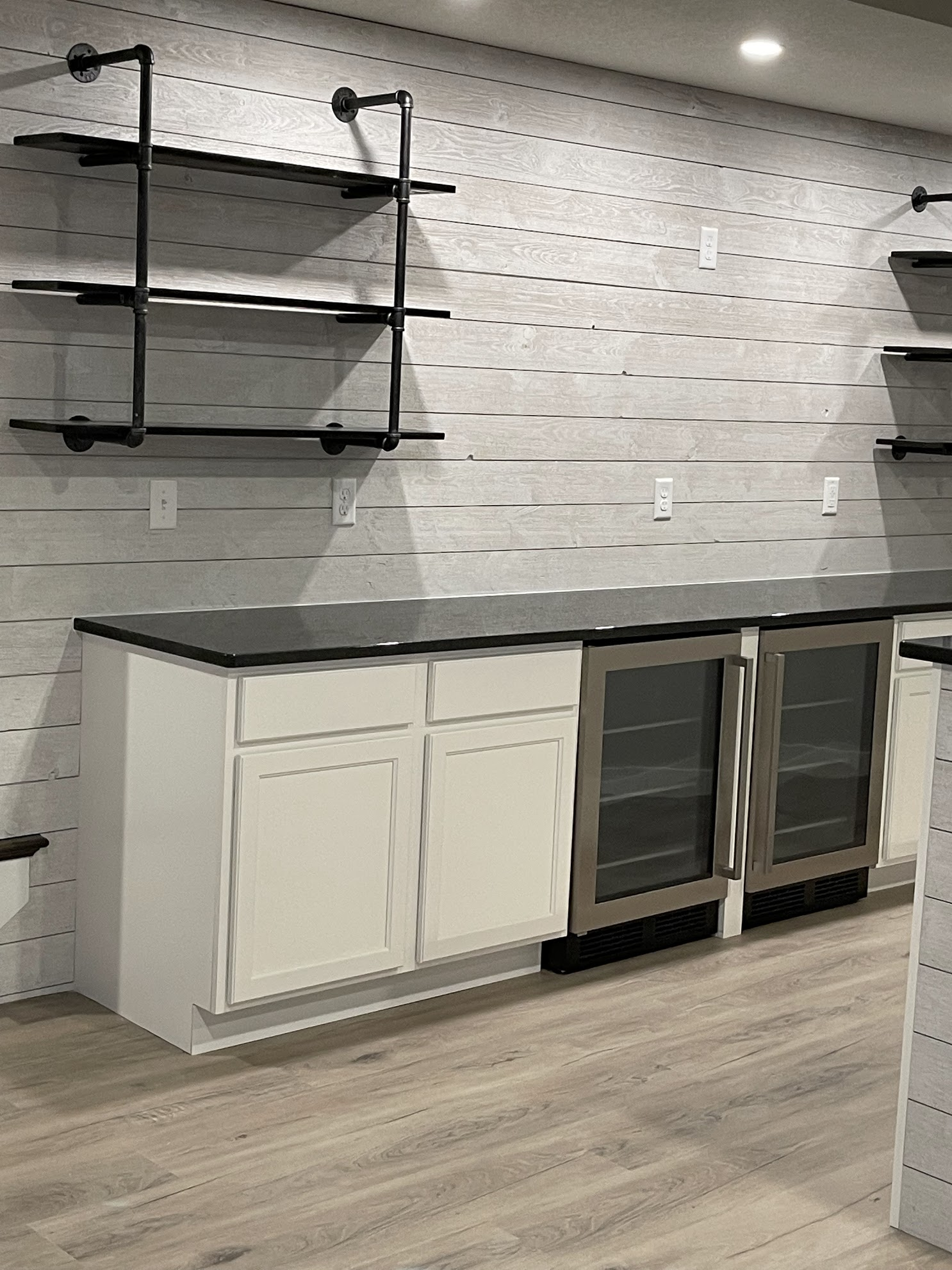 A kitchen with white cabinets , black counter tops , and a refrigerator.