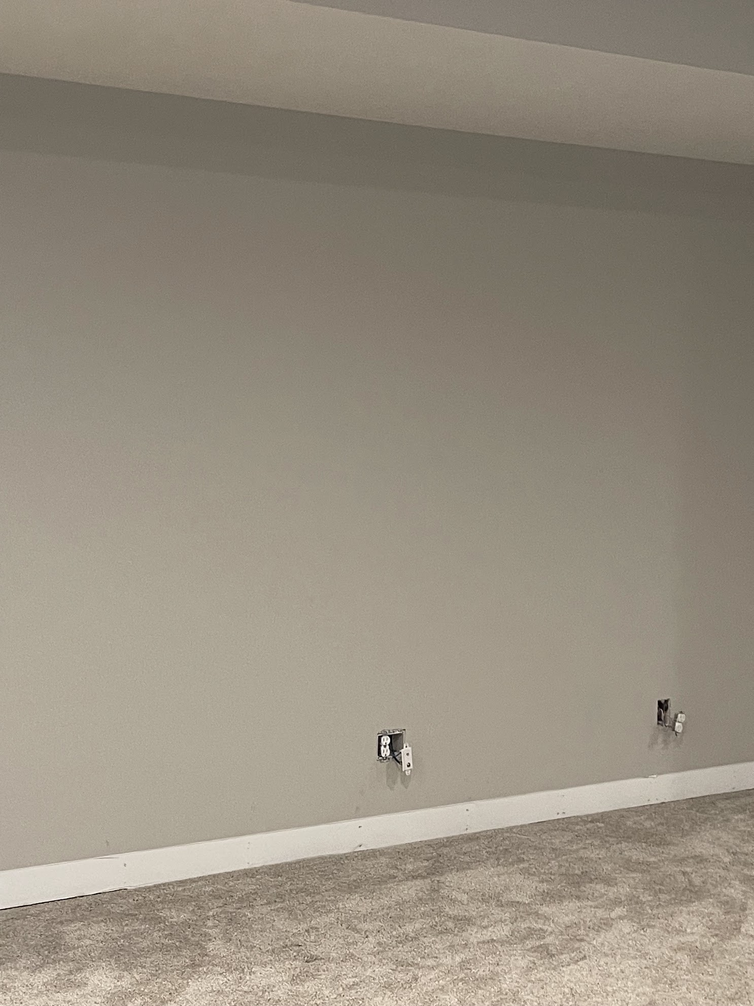 An empty room with a large wall and a carpeted floor.