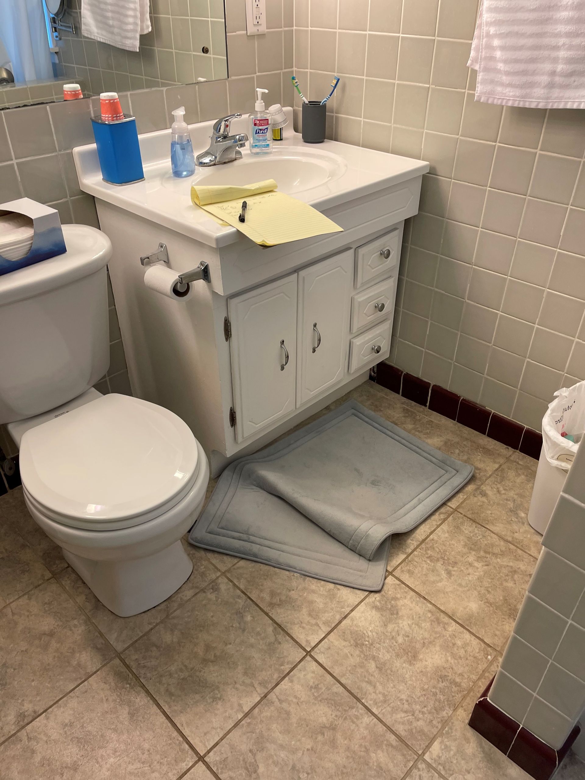 A bathroom with a toilet , sink , and mirror.
