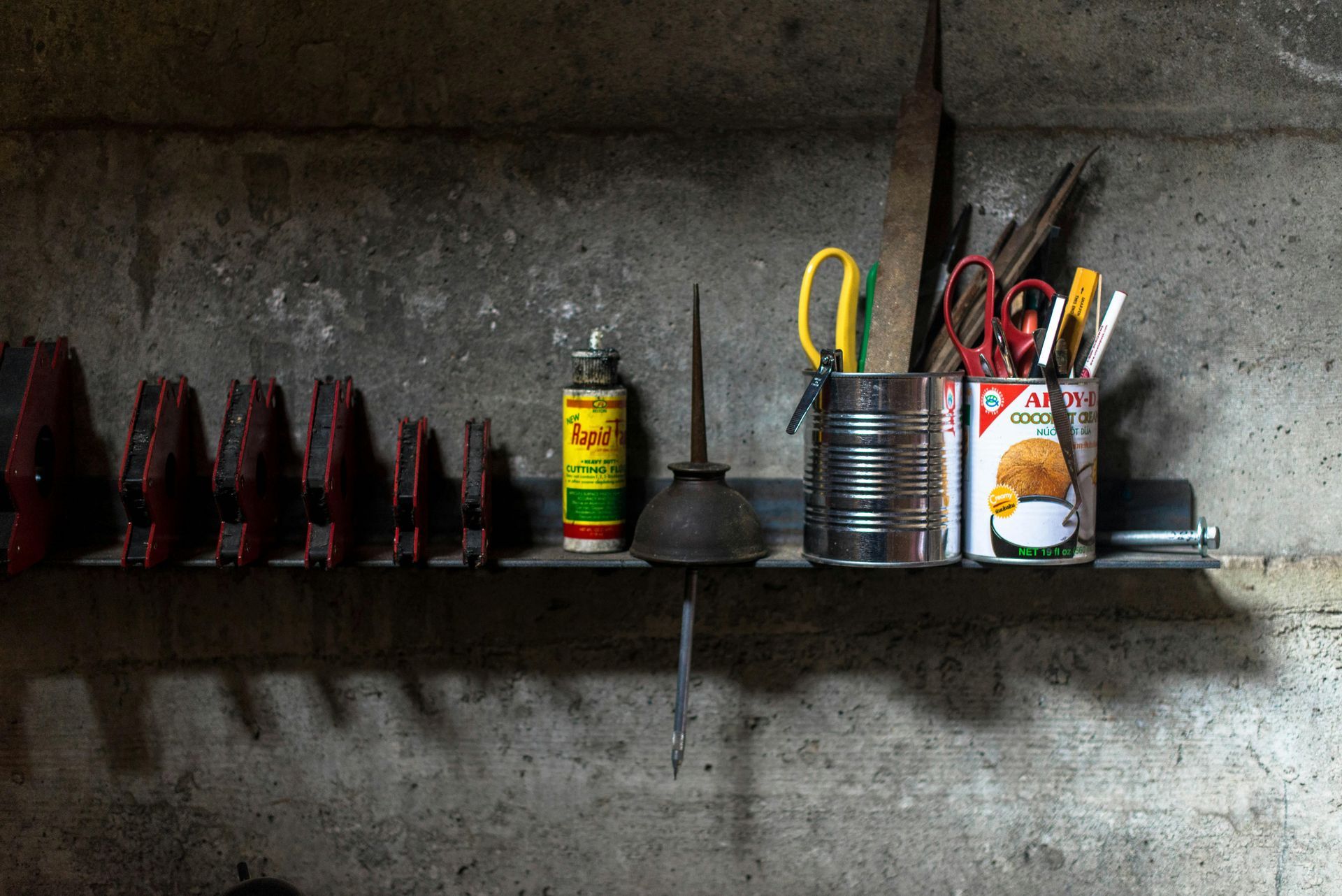 A shelf in a garage with tools and a can of paint