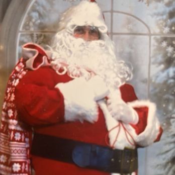 Santa Claus holding a sack of gifts, wearing a red suit and white beard.
