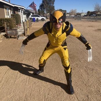 Man in Wolverine costume poses outdoors with claws extended.