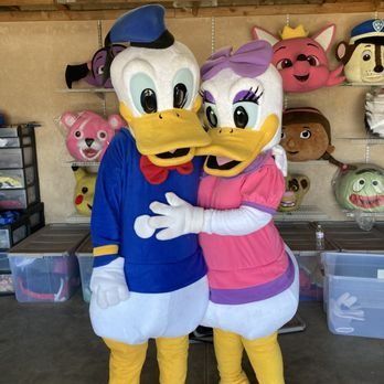 Donald Duck and Daisy Duck in costume, hugging, with other character heads in the background.