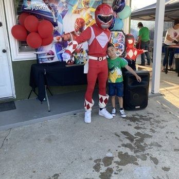 Red Power Ranger posing with a boy at a party, red balloons, superhero theme.