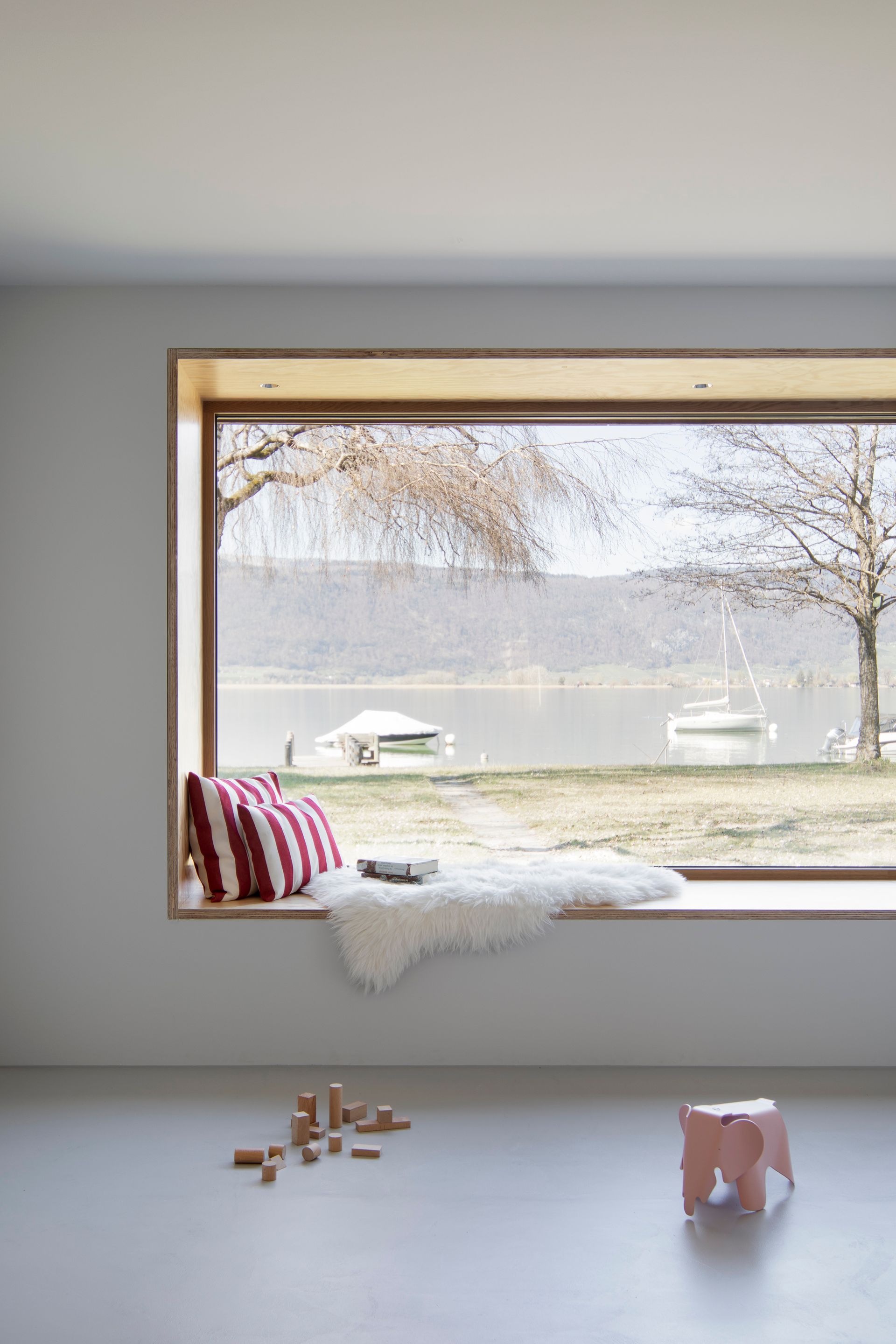 Ein Fensterplatz mit Blick auf einen See in einem Wohnzimmer.