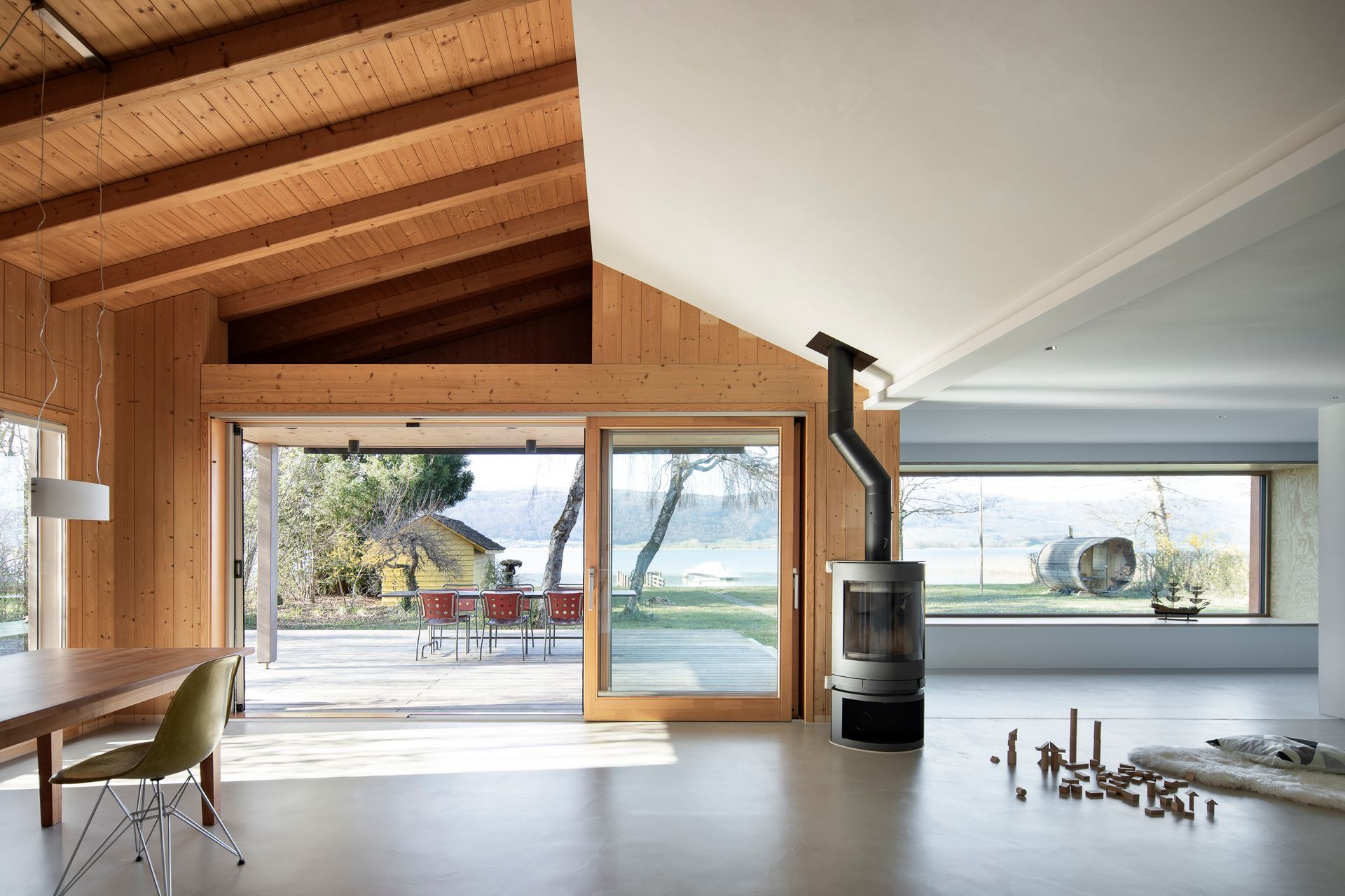 Ein Wohnzimmer mit Holzofen und vielen Fenstern