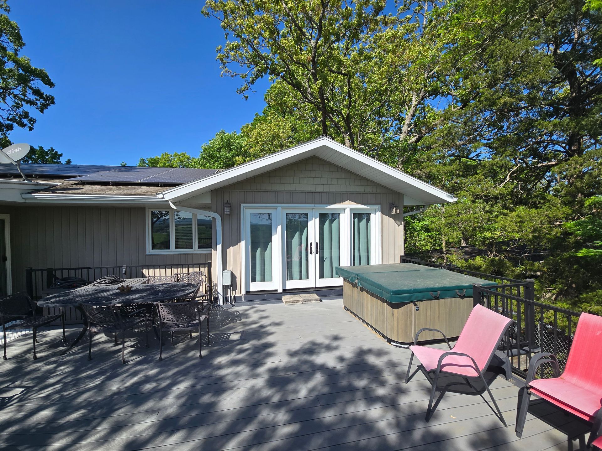 Patio with outdoor seating beside a white house under a blue sky