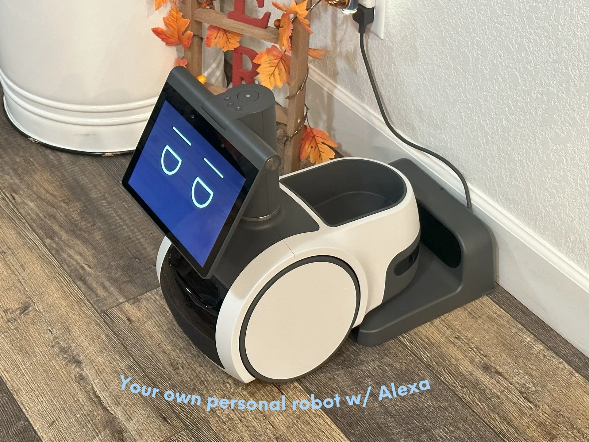 A robot is sitting on a wooden floor next to a wall.