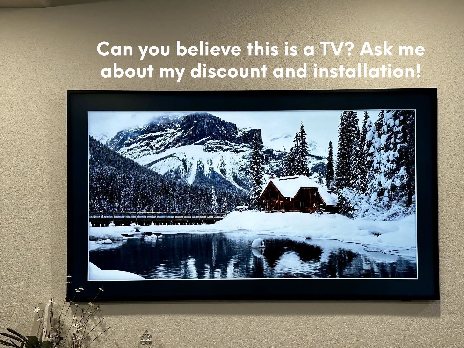 A tv is hanging on a wall with a picture of a snowy landscape on it.
