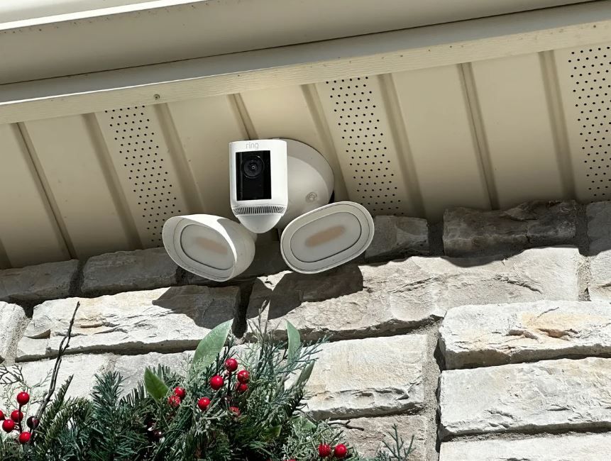 A security camera is mounted on the side of a house.