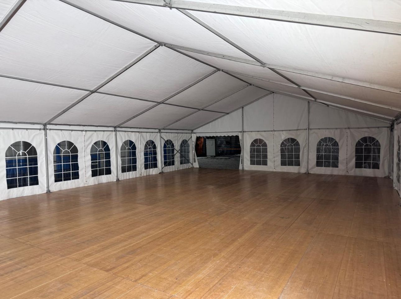 À l'intérieur d'une grande tente événementielle avec un plancher en bois et des parois vitrées cintrées.