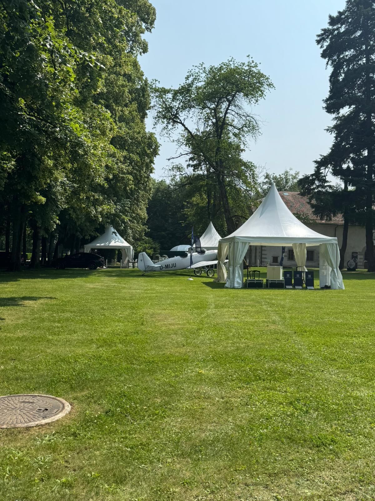Des tentes blanches sur une pelouse entourée d'arbres par une journée ensoleillée.
