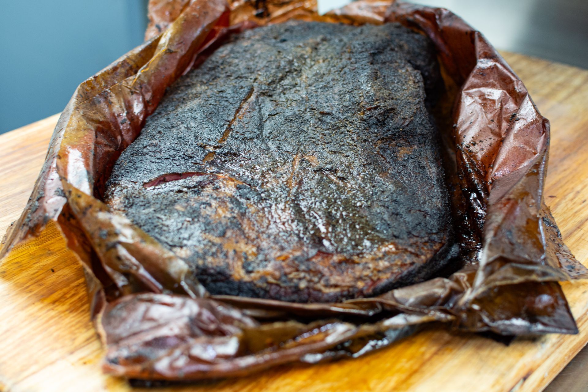 A pulled pork sandwich with coleslaw and carrots on a wooden cutting board.