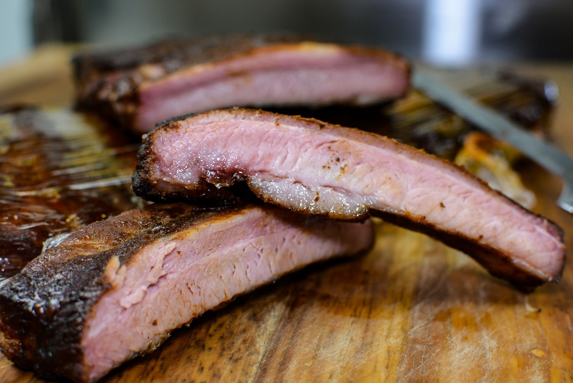 A pulled pork sandwich with coleslaw and carrots on a wooden cutting board.