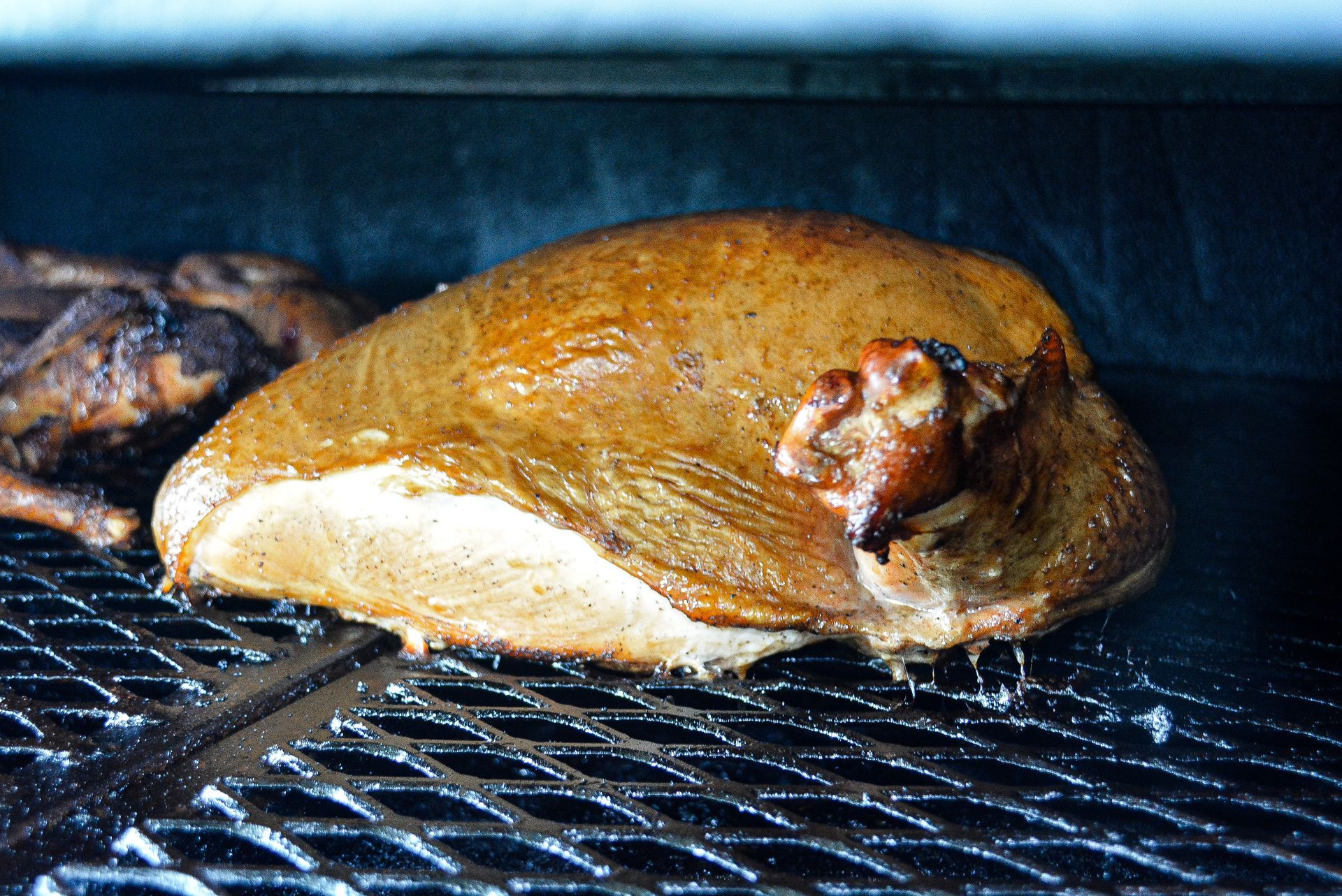 A styrofoam container filled with meat , beans , macaroni and cheese , and pickles.