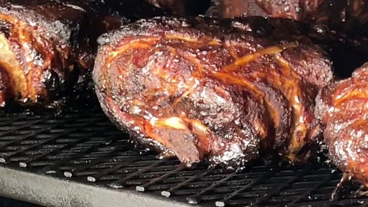 A row of wooden picnic tables with red umbrellas in a gravel area.