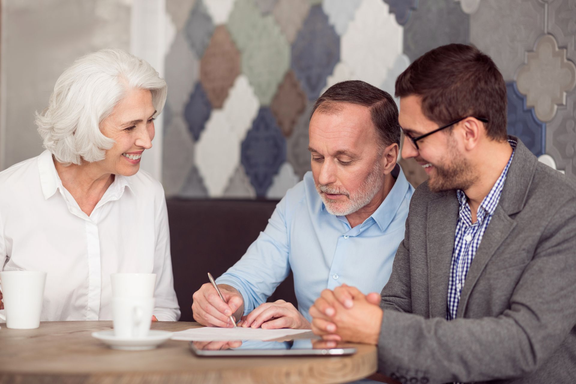 Financial advisor showing a laptop to an elderly couple at a desk.
