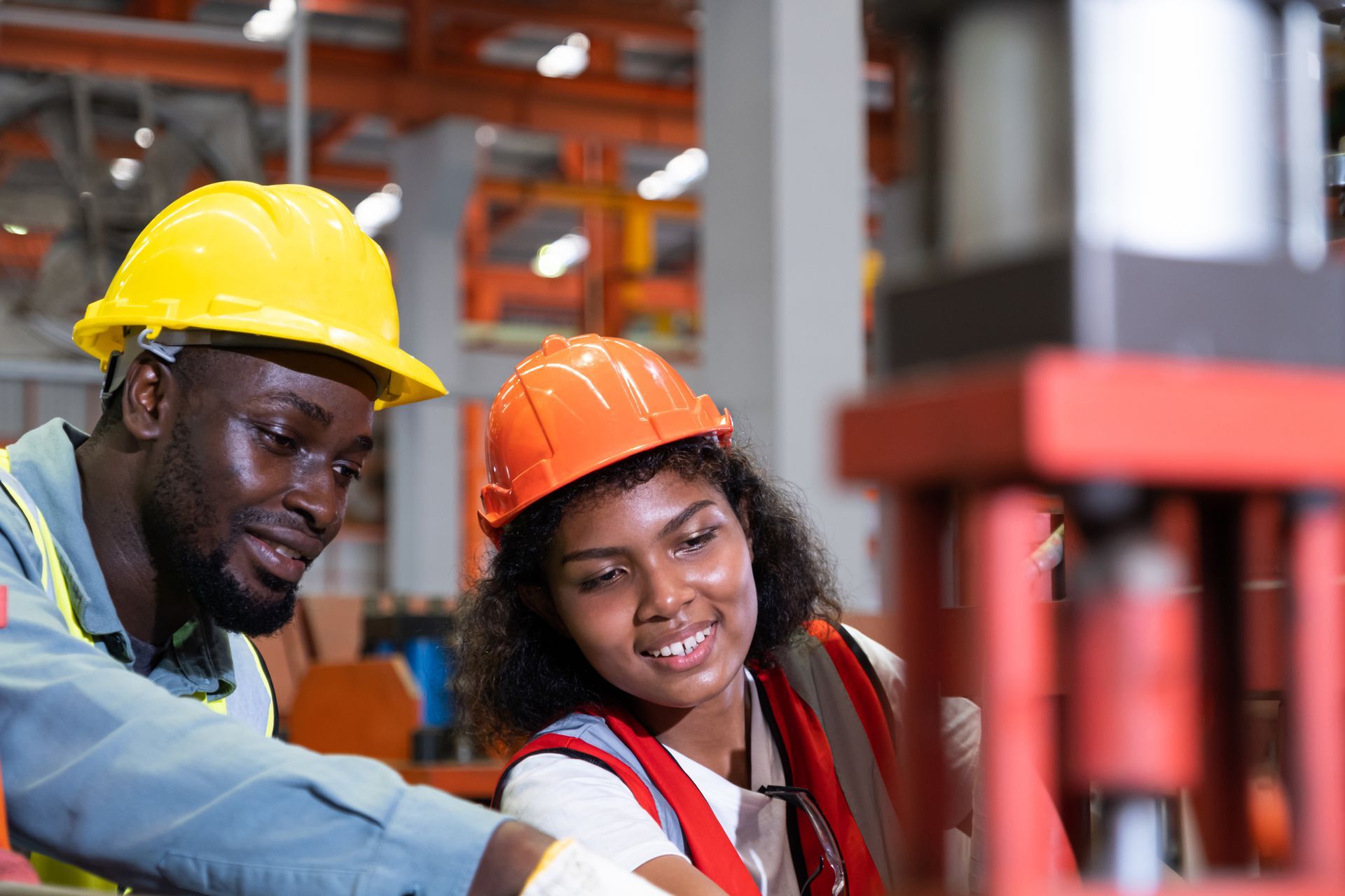 Group of people in yellow hard hats and safety vests standing in a warehouse, arms crossed, looking at the camera.