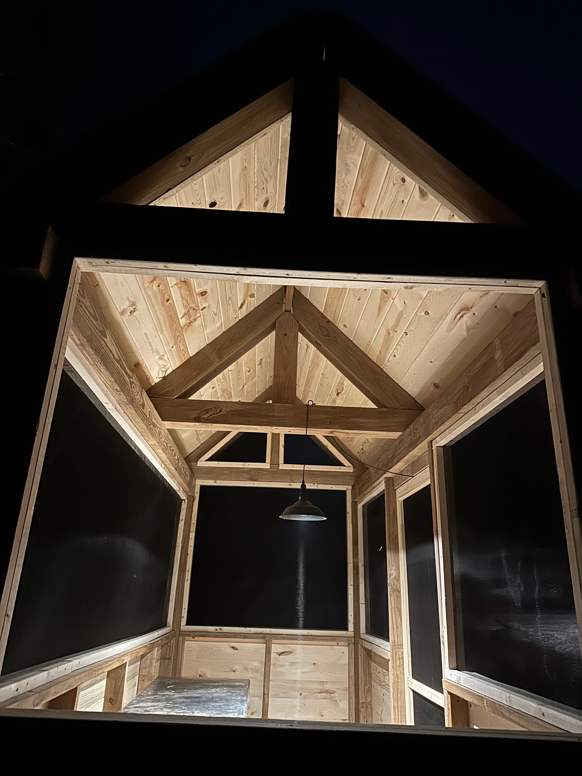 The inside of a wooden building is lit up at night.